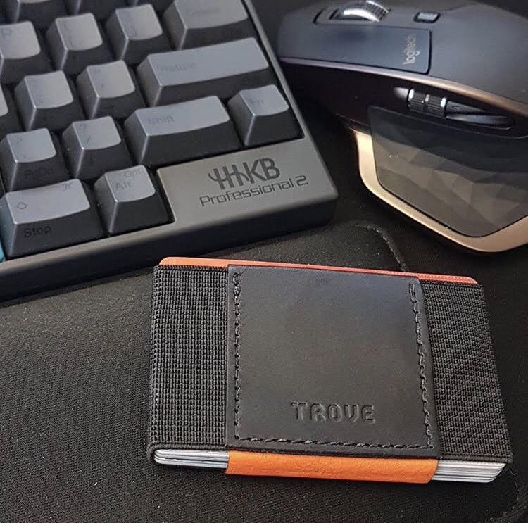Patrick Hener's black and orange TROVE wallet beside a keyboard and mouse. Photograph credited to Patrick Hener.