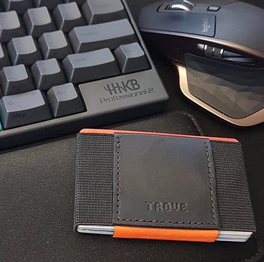 Patrick Hener's black and orange TROVE wallet beside a keyboard and mouse. Photograph credited to Patrick Hener.